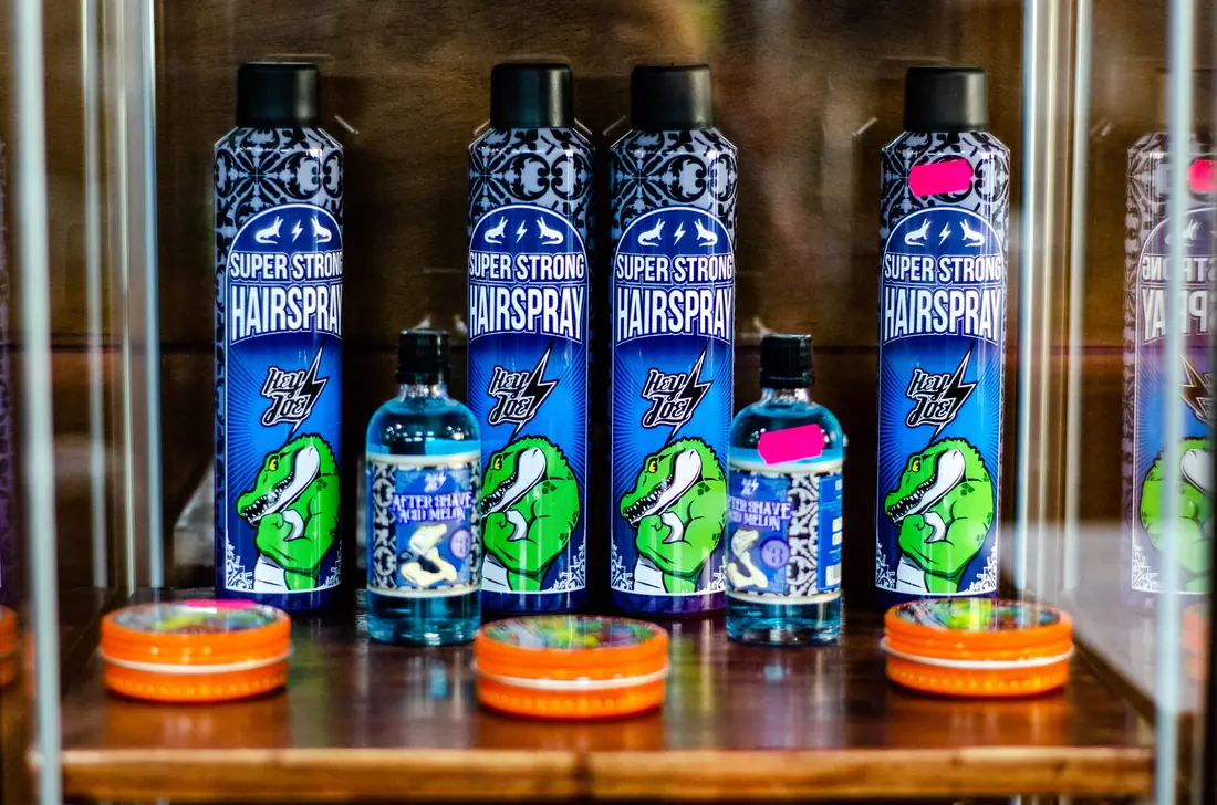 Vitrina con productos de barbería: lacas de fijación fuerte, after shave y ceras de tapa naranja