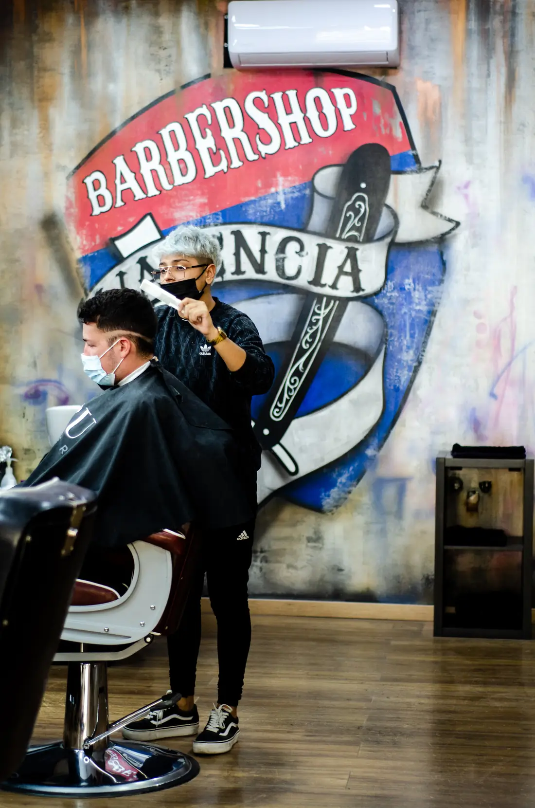 Cliente posando delante del mural del local de Barber Shop Valencia